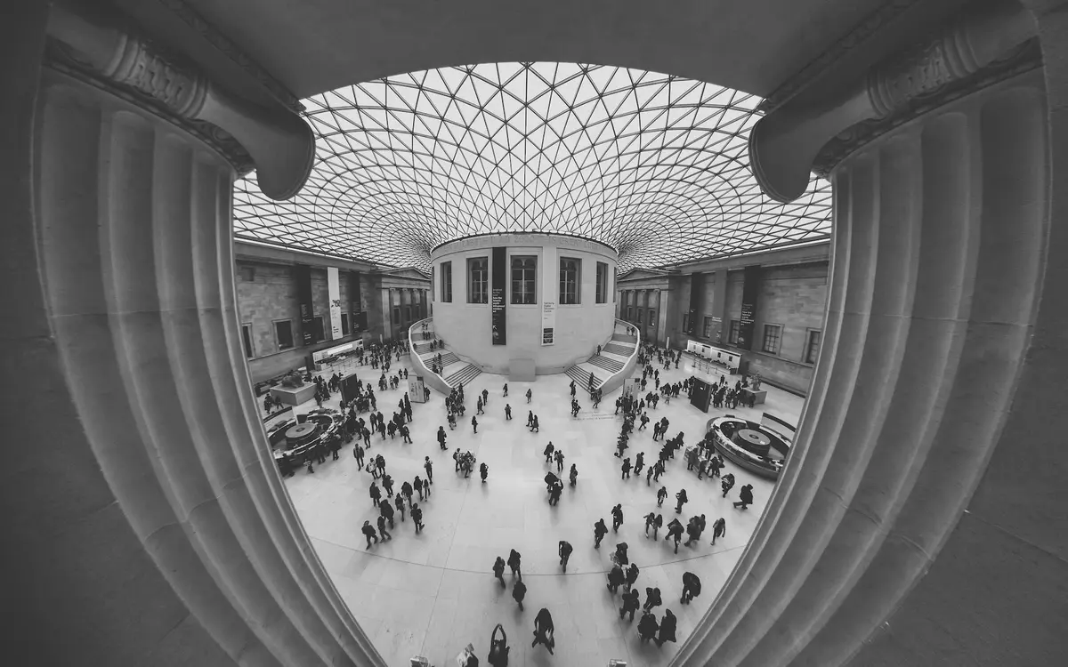 Fisheye photo of an atrium with a glass roof, the columns in the foreground curve around the frame